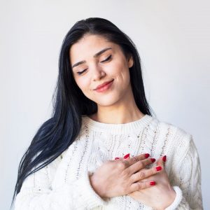 Mujer sonriendo con las manos en el corazón.
